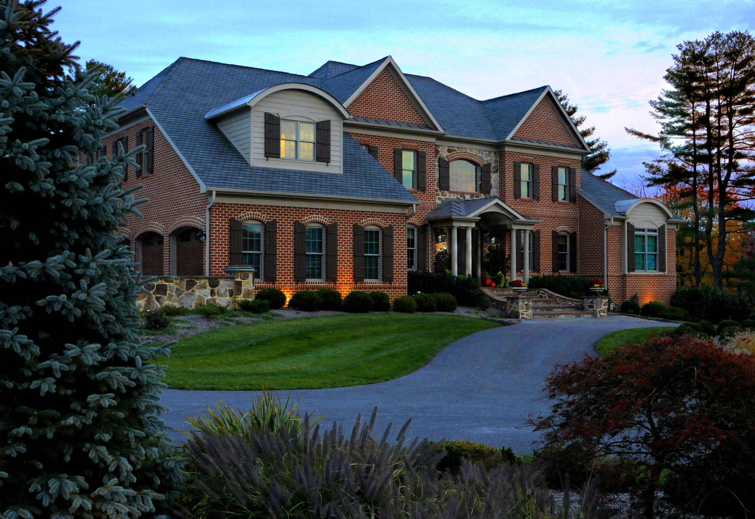 A large brick house with a lush green lawn.